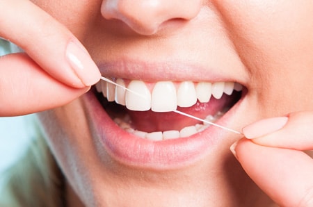 Flossing Habits: Why Is It Important for Adults and Children 1 a person flossing teeth