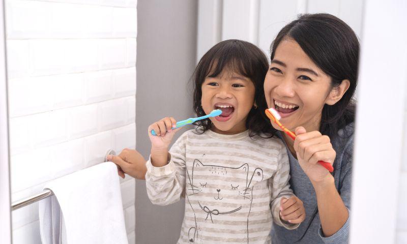 parent kid brushing teeth