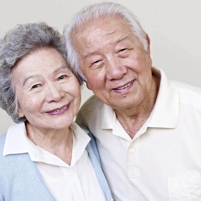 an elderly couple with dental implant smiling